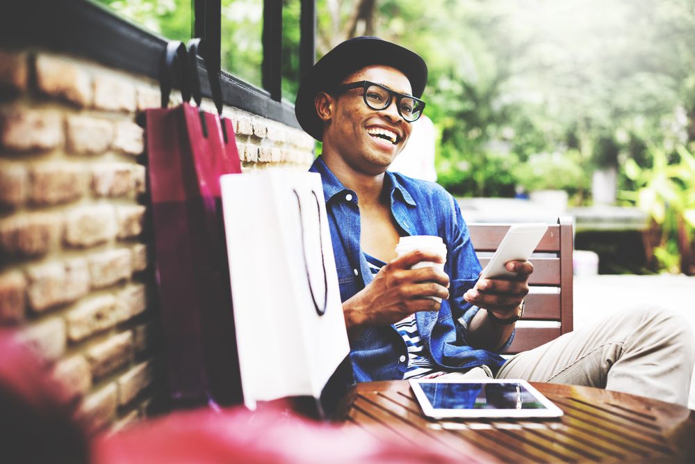 Happy shopper with coffee and bags at outdoor table