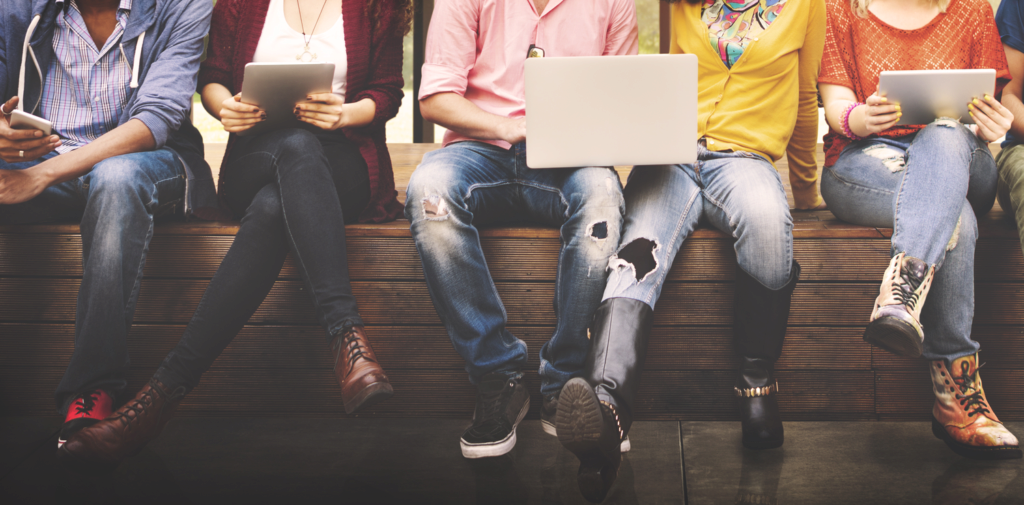 teens with laptops, sitting off bench