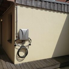 Ladestation für E-Autos an einer Hauswand mit aufgewickeltem Kabel.