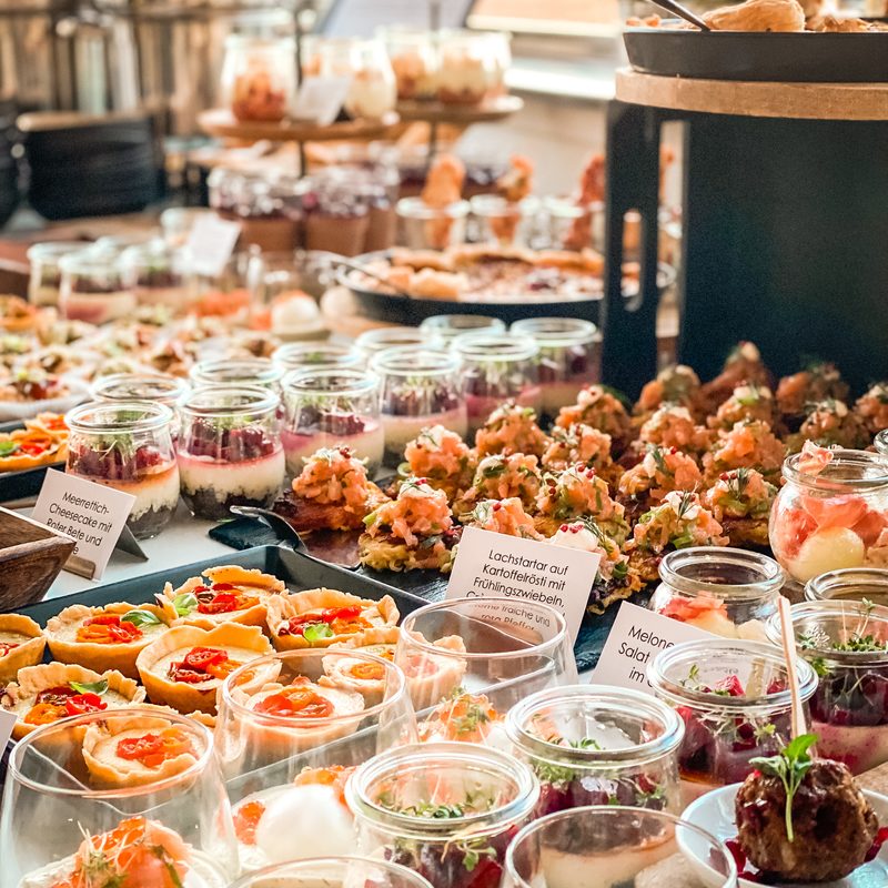 Antipasti- und Salatgläser mit Spießen und Brotaufstrichen