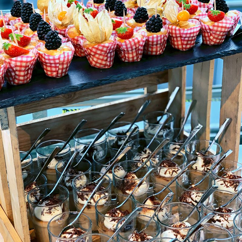 Dessertauswahl im Glas mit Holzregal und roten Details