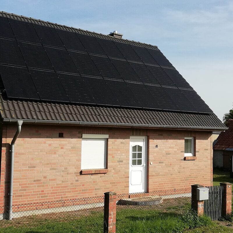 Einfamilienhaus mit heller Fassade und großer, dunkler Photovoltaikanlage auf dem Dach.