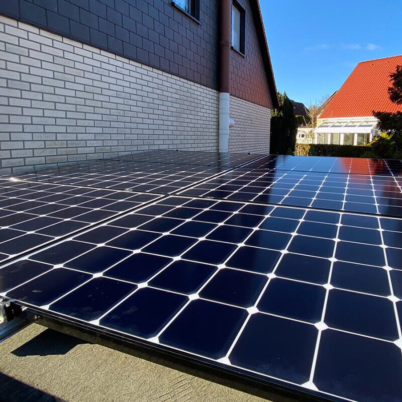 Schräg fotografierte Nahaufnahme von glänzenden Solarpaneelen auf einem Ziegeldach bei sonnigem Wetter.